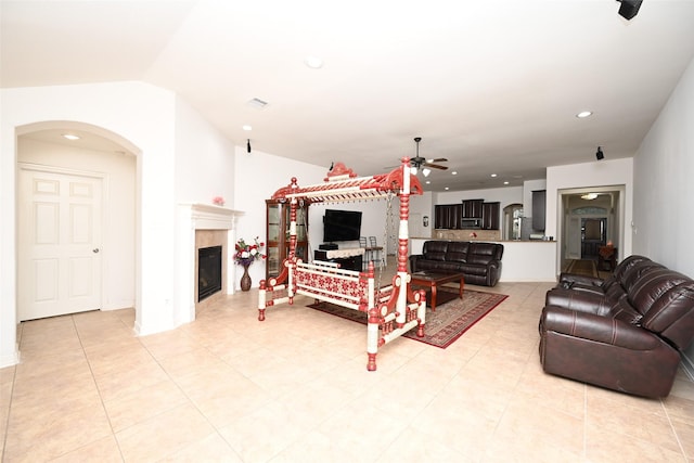 living room featuring a tile fireplace, ceiling fan, and lofted ceiling