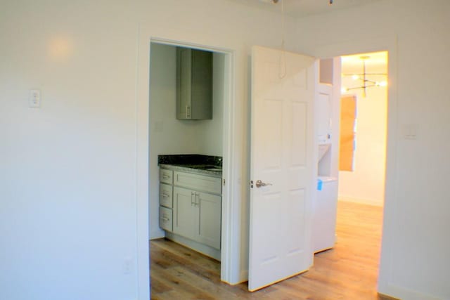 hall with an inviting chandelier and light wood-type flooring