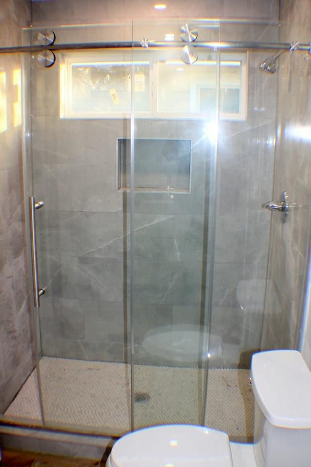 bathroom featuring toilet and a shower with shower door