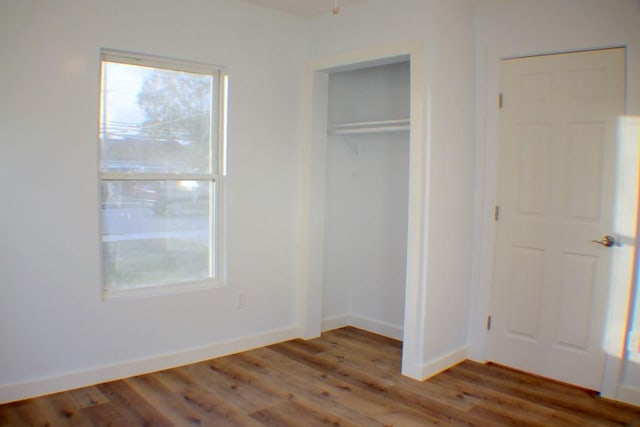 unfurnished bedroom with dark hardwood / wood-style flooring and a closet