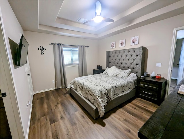 bedroom with a tray ceiling, ceiling fan, and hardwood / wood-style flooring