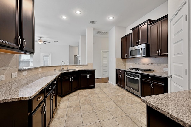 kitchen with sink, ceiling fan, light stone countertops, dark brown cabinets, and stainless steel appliances