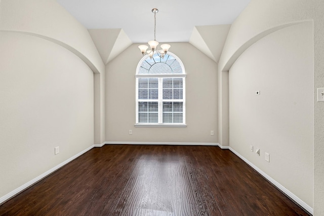 unfurnished room featuring lofted ceiling, dark wood-type flooring, and an inviting chandelier