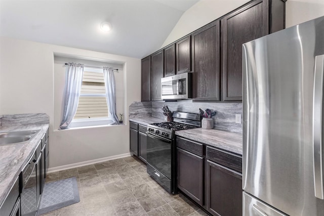 kitchen featuring appliances with stainless steel finishes, dark brown cabinets, vaulted ceiling, and sink