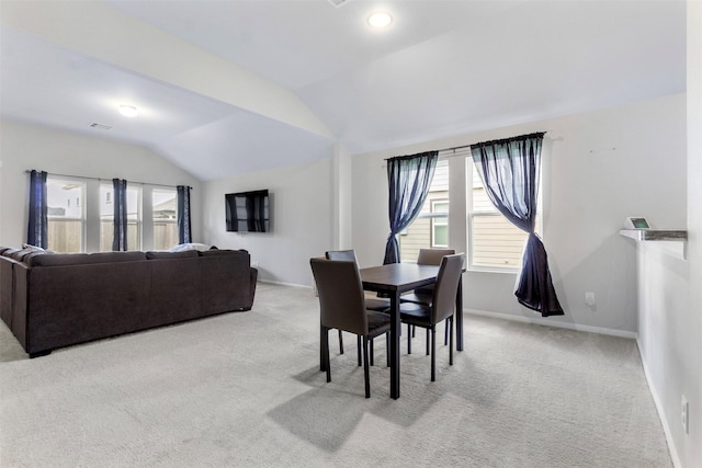 carpeted dining space featuring vaulted ceiling