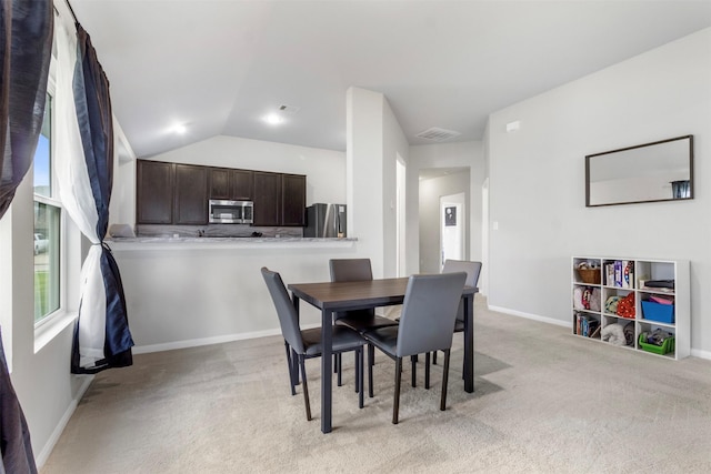 dining area featuring light carpet and vaulted ceiling