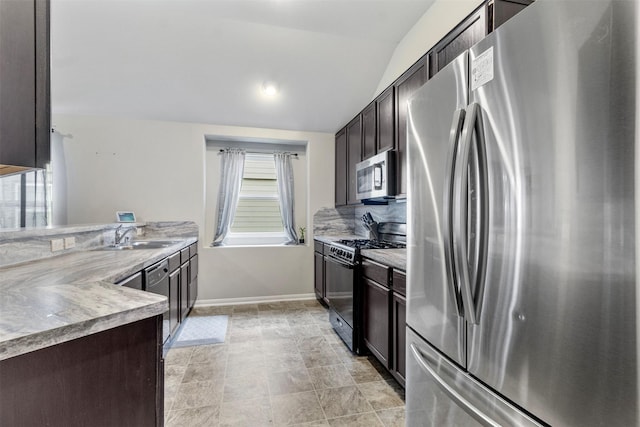 kitchen featuring stainless steel appliances, sink, lofted ceiling, and dark brown cabinetry