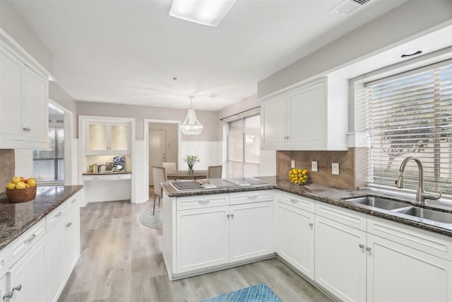 kitchen featuring kitchen peninsula, white cabinetry, and hanging light fixtures