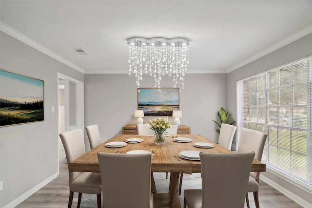 dining area with a chandelier, wood-type flooring, and crown molding