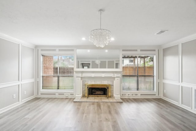 unfurnished living room featuring a fireplace, wood-type flooring, an inviting chandelier, and crown molding