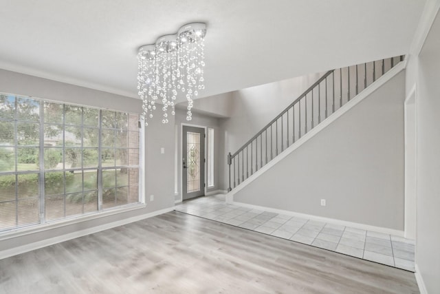 entryway featuring light hardwood / wood-style flooring, ornamental molding, and a notable chandelier