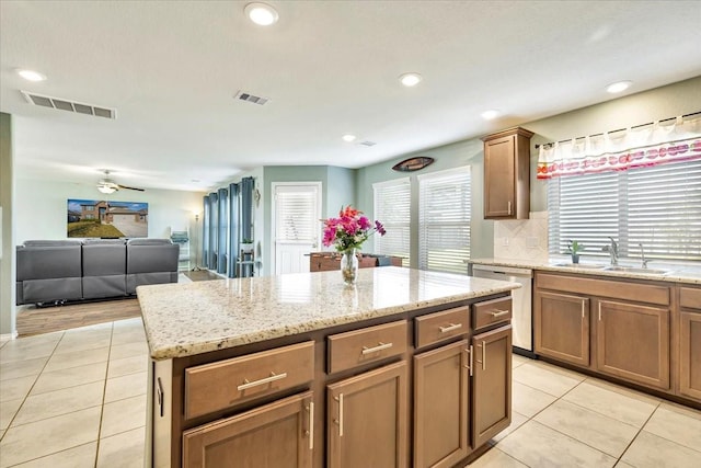 kitchen with sink, stainless steel dishwasher, light tile patterned floors, plenty of natural light, and a kitchen island