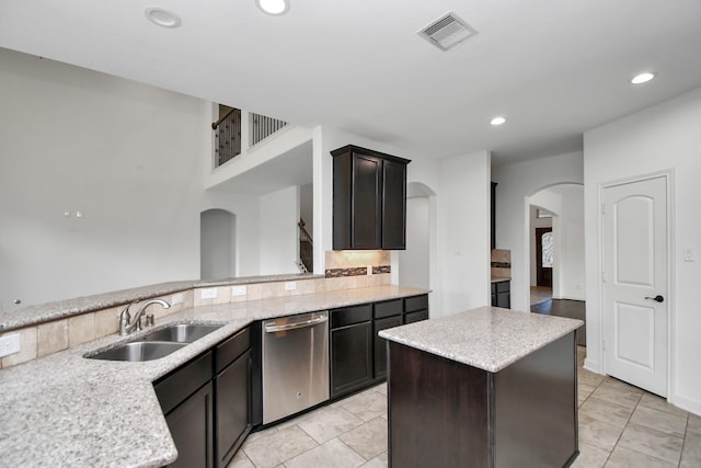 kitchen with dishwasher, a center island, light stone counters, and sink