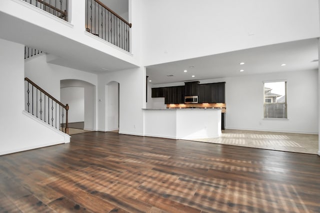 unfurnished living room with a towering ceiling and dark wood-type flooring