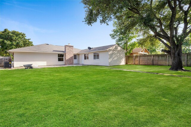 back of property with central AC unit and a yard