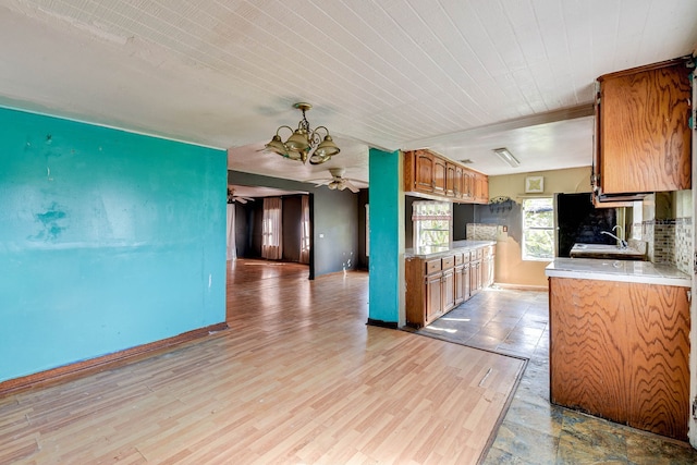 kitchen with tasteful backsplash, light hardwood / wood-style flooring, and ceiling fan with notable chandelier