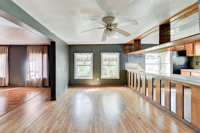 kitchen featuring stainless steel refrigerator, ceiling fan, light hardwood / wood-style floors, and a textured ceiling