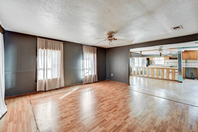 unfurnished living room featuring a textured ceiling, light hardwood / wood-style floors, and ceiling fan