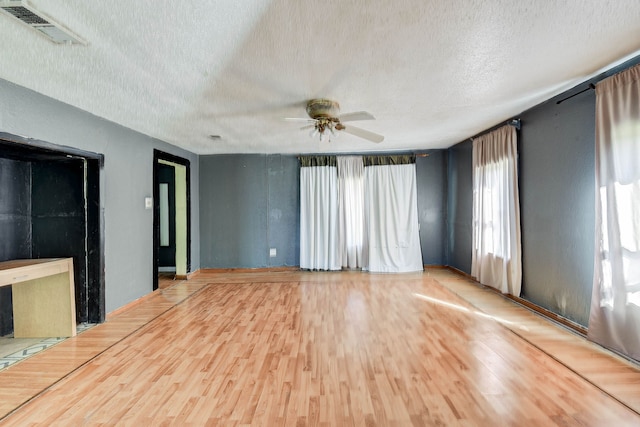 unfurnished living room with wood-type flooring, a textured ceiling, and ceiling fan