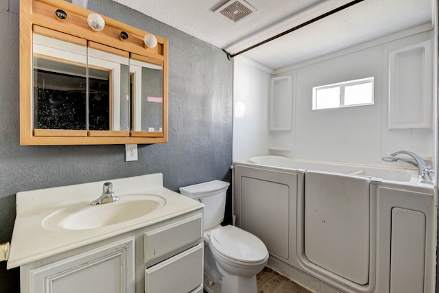 bathroom featuring a textured ceiling, vanity, toilet, and a bathing tub