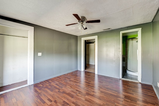 unfurnished bedroom featuring a textured ceiling, dark hardwood / wood-style flooring, and ceiling fan