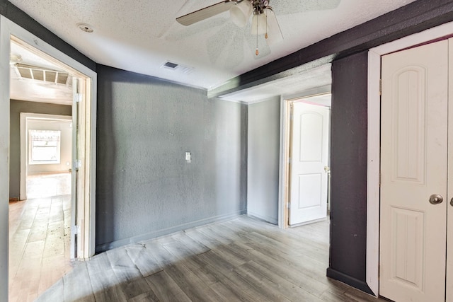 unfurnished room featuring ceiling fan, light wood-type flooring, and a textured ceiling