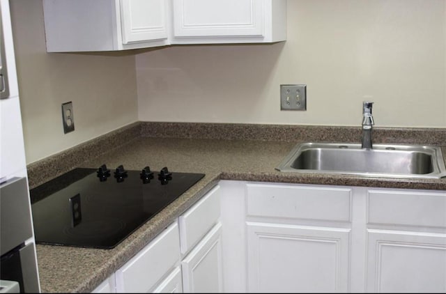 kitchen featuring black electric cooktop, white cabinetry, and sink