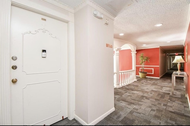 hall featuring dark carpet and a textured ceiling