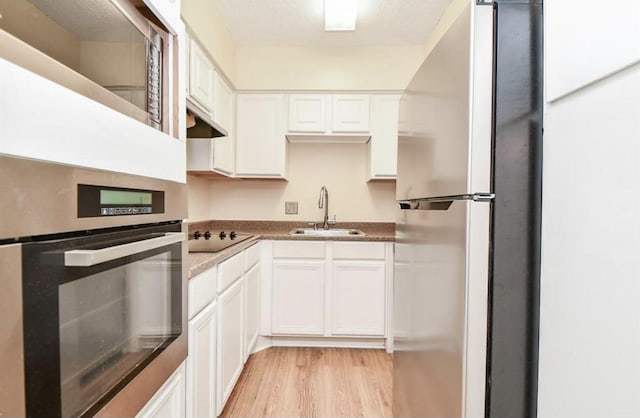 kitchen featuring white cabinets, sink, appliances with stainless steel finishes, and light hardwood / wood-style flooring