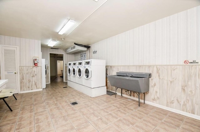 laundry area featuring wooden walls and tile patterned flooring