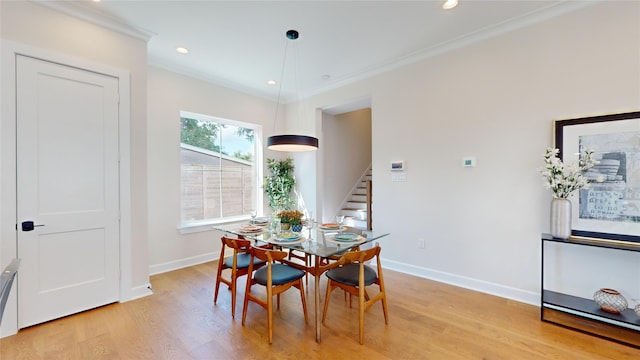 dining space with light wood-type flooring and ornamental molding