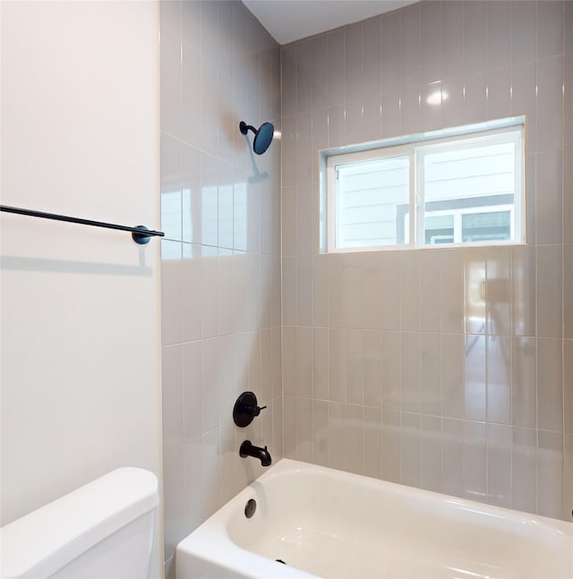 bathroom featuring toilet and tiled shower / bath