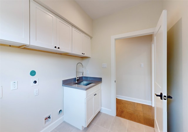 washroom featuring sink, cabinets, hookup for an electric dryer, hookup for a washing machine, and light tile patterned flooring