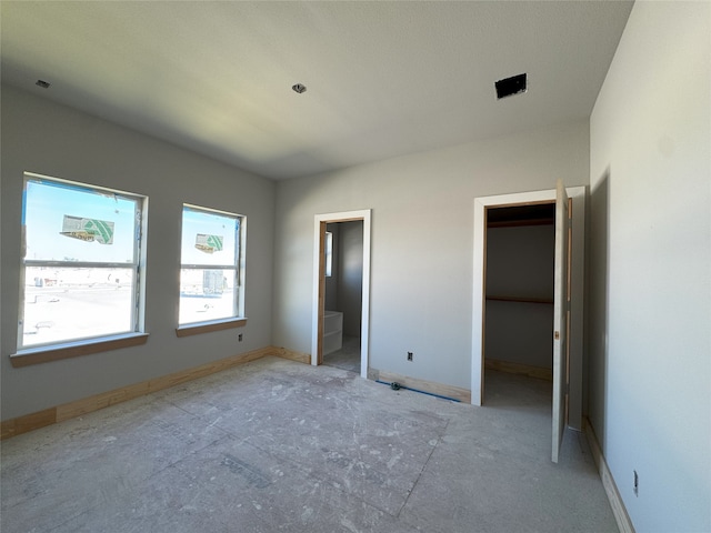 unfurnished bedroom featuring a walk in closet and connected bathroom