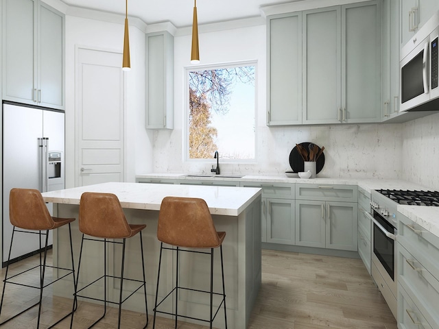 kitchen with light stone countertops, sink, pendant lighting, high quality appliances, and a kitchen island