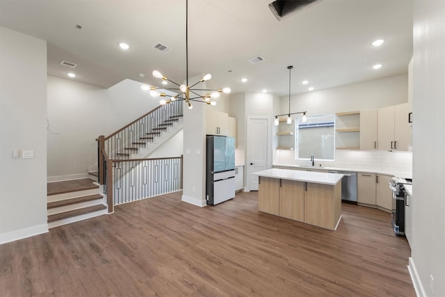 kitchen featuring wood finished floors, a kitchen island, open shelves, a sink, and appliances with stainless steel finishes