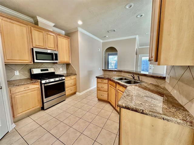 kitchen featuring decorative backsplash, appliances with stainless steel finishes, sink, light brown cabinets, and dark stone countertops