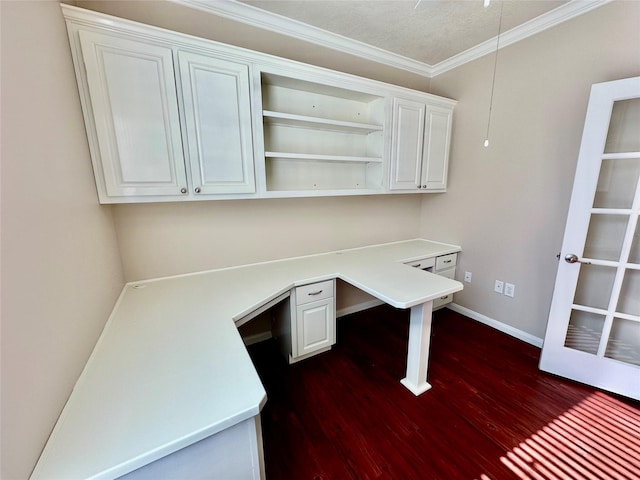 unfurnished office with dark wood-type flooring, built in desk, a textured ceiling, and ornamental molding