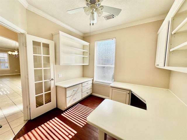 unfurnished office featuring a textured ceiling, crown molding, dark tile patterned floors, and ceiling fan with notable chandelier