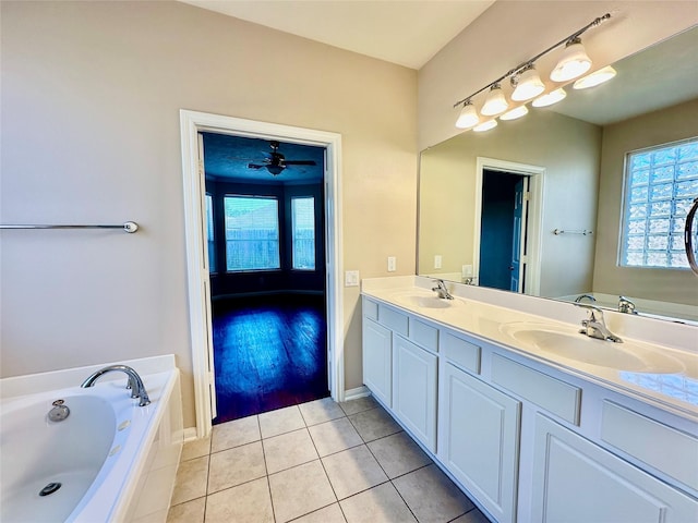 bathroom with tile patterned flooring, ceiling fan, vanity, and tiled bath