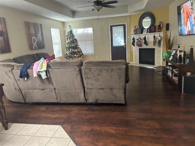 living room featuring tile patterned flooring, ceiling fan, and a tray ceiling