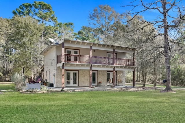 rear view of house with a balcony, a lawn, a patio area, and french doors