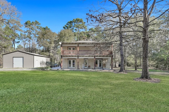 rear view of house featuring a yard, a balcony, french doors, and a garage