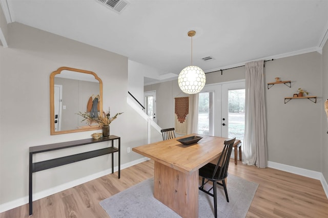 dining space featuring french doors, ornamental molding, and light hardwood / wood-style flooring