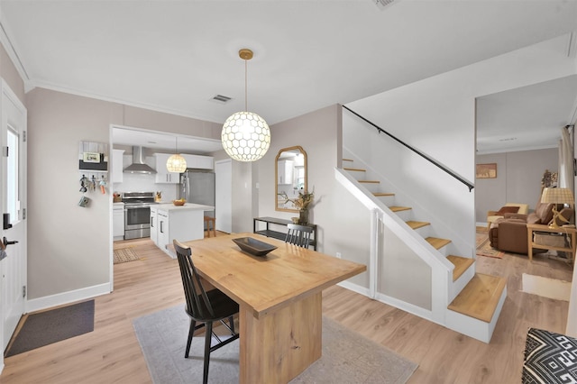 dining area featuring light wood-type flooring and crown molding