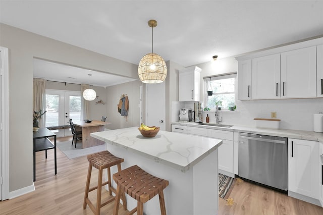 kitchen with sink, french doors, stainless steel dishwasher, decorative light fixtures, and white cabinets