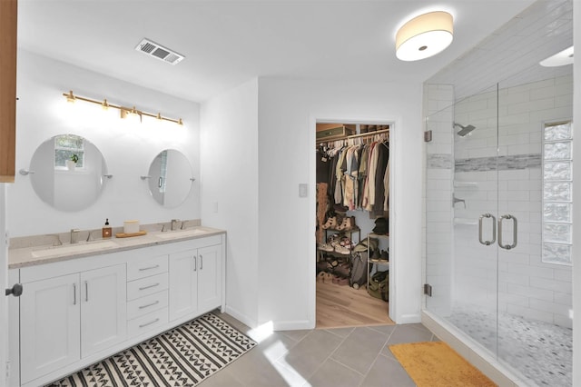 bathroom featuring tile patterned flooring, vanity, and a shower with shower door