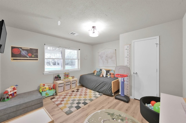 bedroom featuring a textured ceiling and light hardwood / wood-style flooring