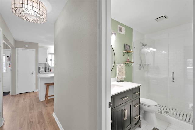 bathroom with hardwood / wood-style floors, vanity, a shower with shower door, and toilet