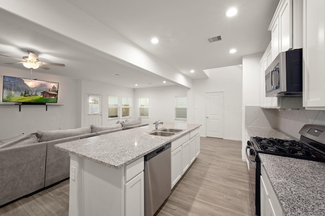 kitchen featuring stainless steel appliances, white cabinetry, a center island with sink, and sink